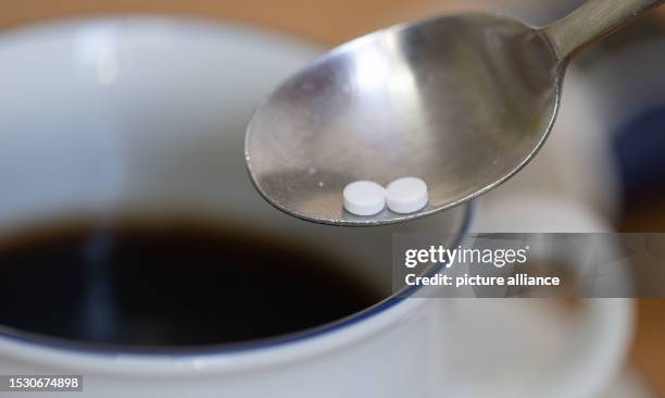July 2023, Saxony, Leipzig: A spoon with two sweetener tablets is seen above a cup of coffee. A sweetener commonly used in soft drinks, yogurt and...