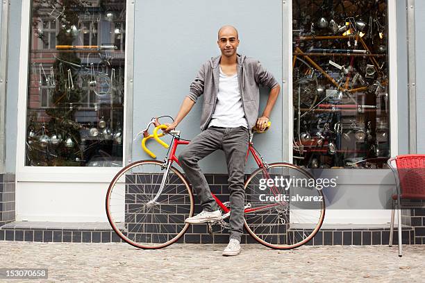 jovem rapaz moderno com uma bicicleta - loja de bicicletas imagens e fotografias de stock