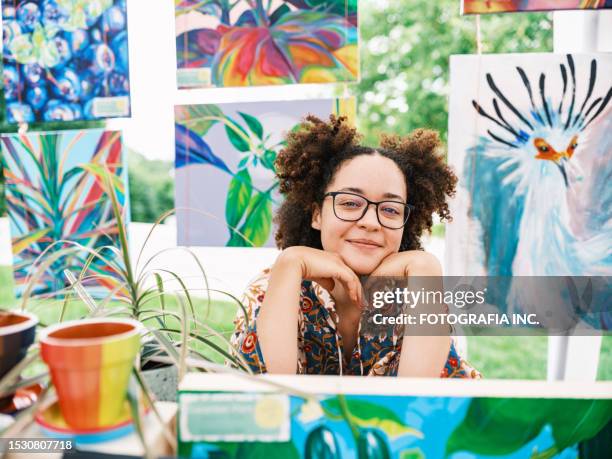 joven artista latina vendiendo su arte en un mercado al aire libre - exposición artística fotografías e imágenes de stock