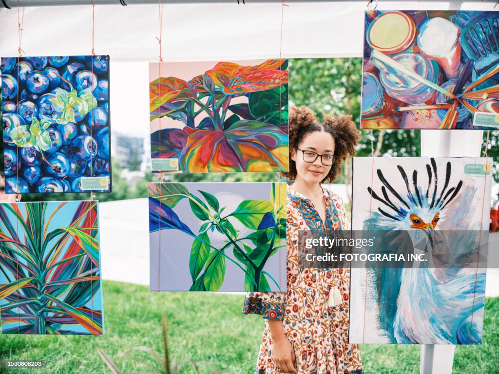 Junge lateinamerikanische Künstlerin, die ihre Kunst auf dem Outdoor-Markt verkauft