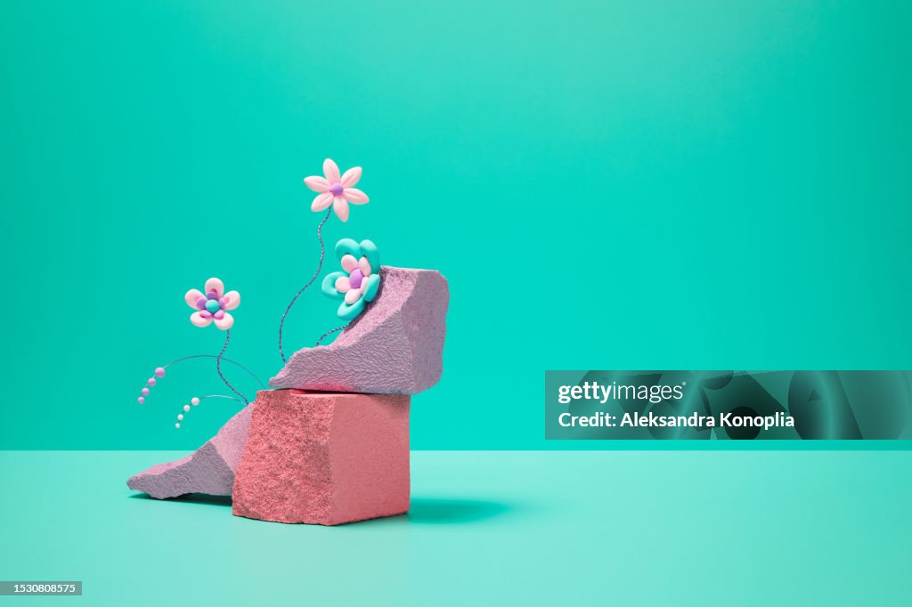 Abstract 3d scene showcase - bold color-blocked composition with pink kawaii flowers and empty podium made of light violet and coral rocks on turquoise background with copy space.