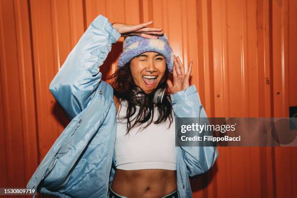 portrait of a young adult woman looking at camera against an orange wall in the city - all hip hop models stock pictures, royalty-free photos & images