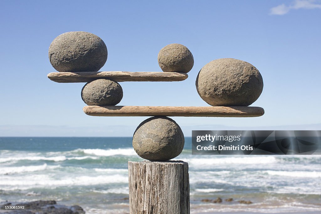 Rocks balancing on driftwood, sea in background