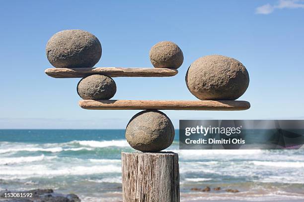 rocks balancing on driftwood, sea in background - stone concept stockfoto's en -beelden