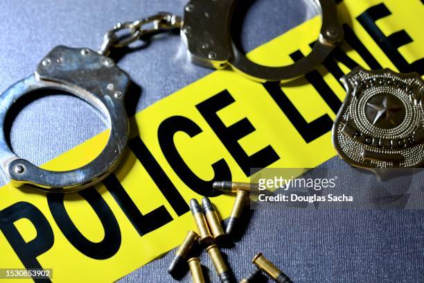 crime and justice concepts - handcuffs, badge, bullets, and caution tape - armed police stock pictures, royalty-free photos & images
