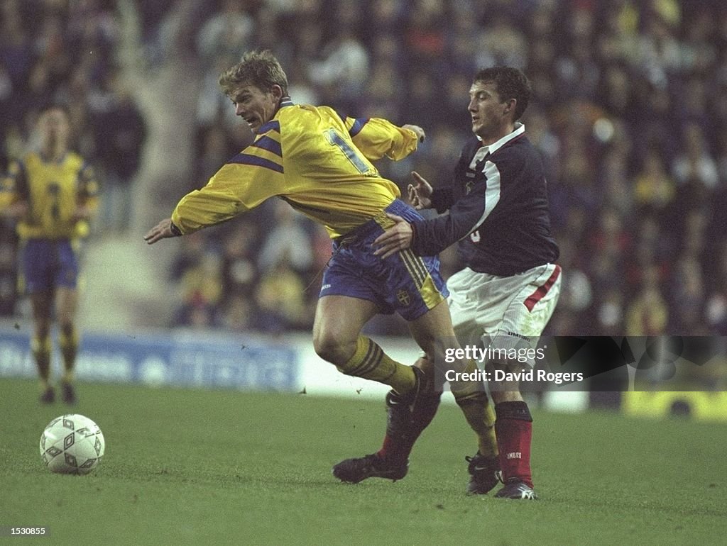 Jesper Blomqvist of Sweden is held back by Billy McKinlay of Scotland