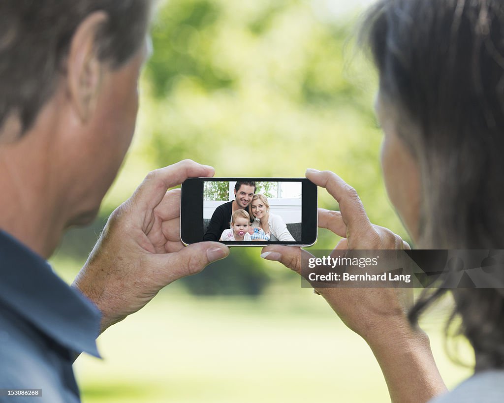 Grandparents looking at family photo on smartphone
