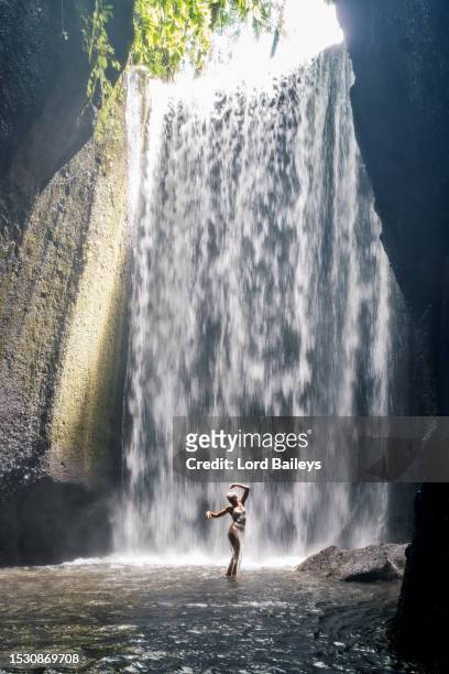 woman staying under waterfall, bali - bali waterfall stock pictures, royalty-free photos & images