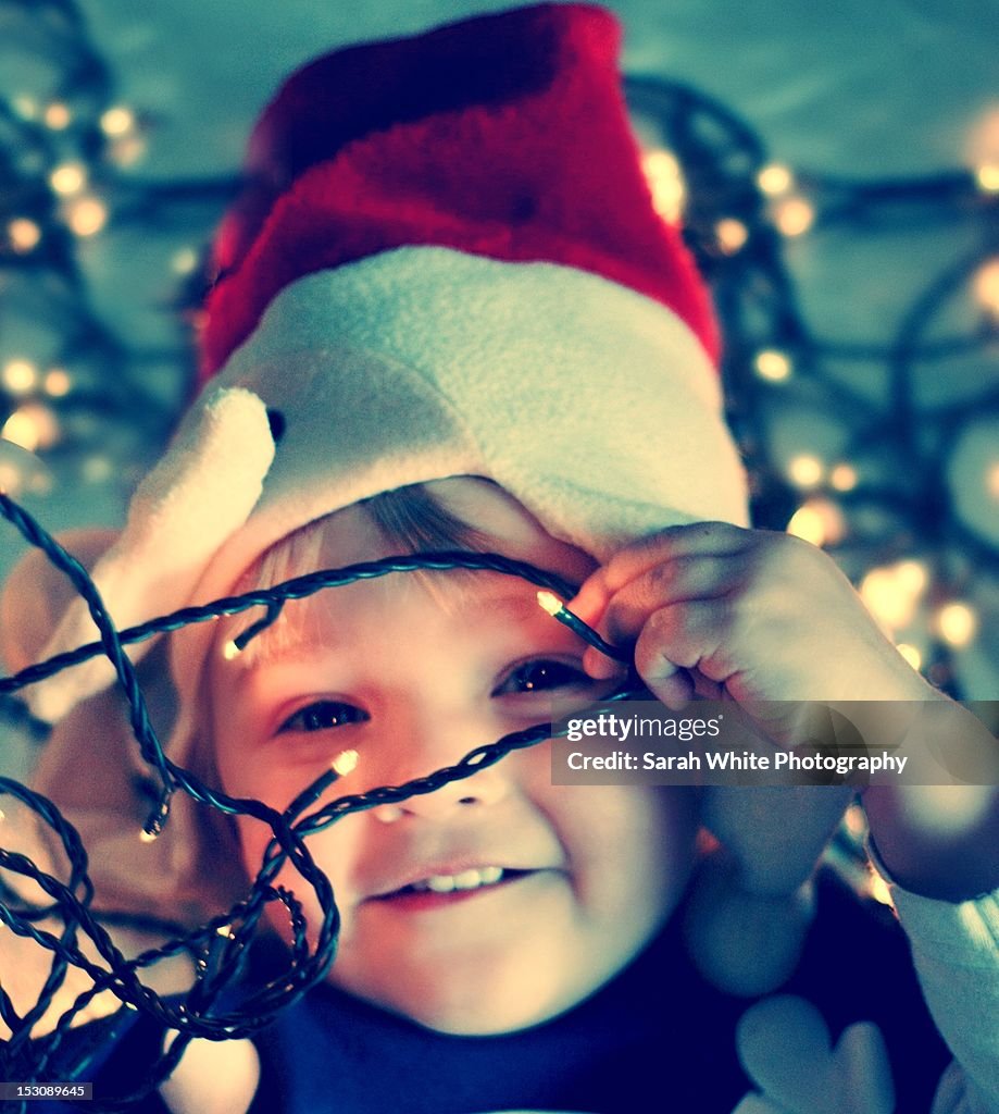 Young boy amongst Christmas lights