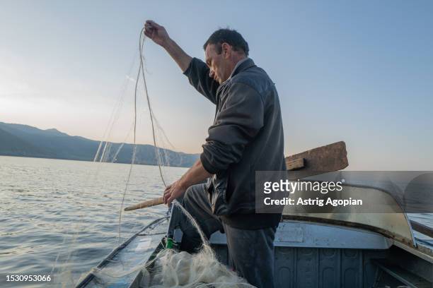 Local fisherman on his boat in the early morning, taking out his fishing net on July 9, 2023 in Artanish, Armenia. Armenia's iconic lake is shrinking...