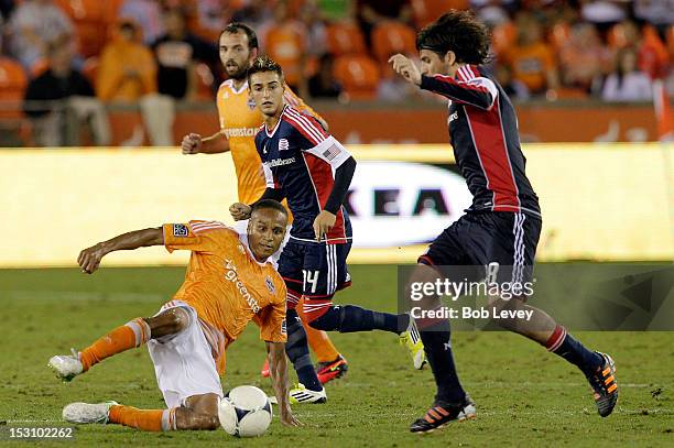 Ricardo Clark of the Houston Dynamo slides in front of Juan Toja of the New England Revolution in an attempt to kick the ball away at BBVA Compass...