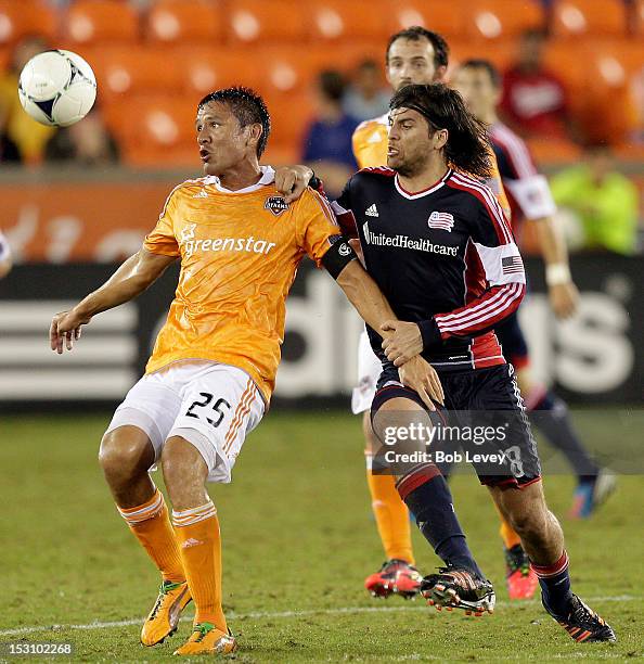 Brian Ching of the Houston Dynamo keeps his eyes on the ball as he is pressured by Juan Tojoa of the New England Revolution at BBVA Compass Stadium...