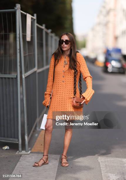 Chloe Harrouche seen outside Chanel show wearing black sunnies, gold hoop earrings, big Chanel chai necklace, orange knitted dress with long sleeves,...