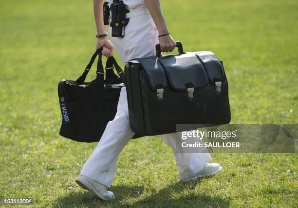 White House military aide and member of the US Navy carries a briefcase known as the "football," containing emergency nuclear weapon codes, as US...