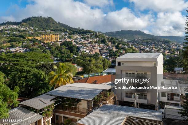 panoramic view of the city with houses, buildings, and trees surrounded by green mountains on a sunny day - honduras 個照片及圖片檔