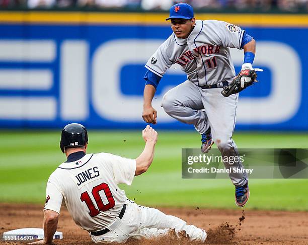 Ruben Tejada of the New York Mets turns a double play over Chipper Jones of the Atlanta Braves in the seventh inning at Turner Field on September 30,...