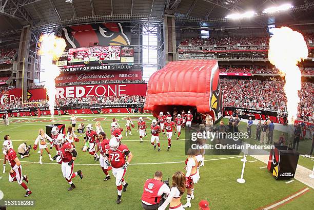 The Arizona Cardinals run out onto the field during player introductions to the NFL game against the Miami Dolphins at the University of Phoenix...