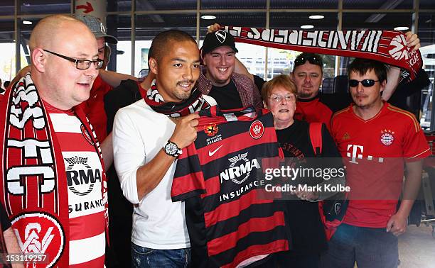 Shinji Ono holds a Western Sydney Wanderers playing shirt as he poses with supporters after his arrival at Sydney International Airport on October 1,...