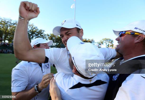 Martin Kaymer of Europe celebrates with Rory McIlroy and Peter Hanson after holing the decisive putt on the 18th green during the Singles Matches for...