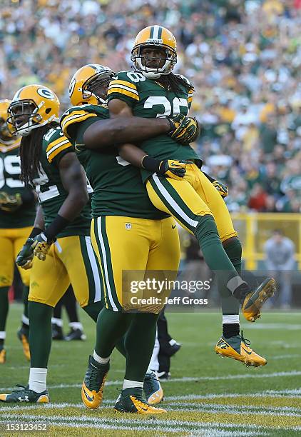 Cornerback Tramon Williams of the Green Bay Packers is picked up by teammate B.J. Raji after breaking up a pass against the New Orleans Saints in the...