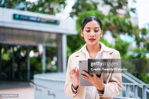asian businesswoman using a digital tablet while working outdoors in the city - cuestionario fotografías e imágenes de stock