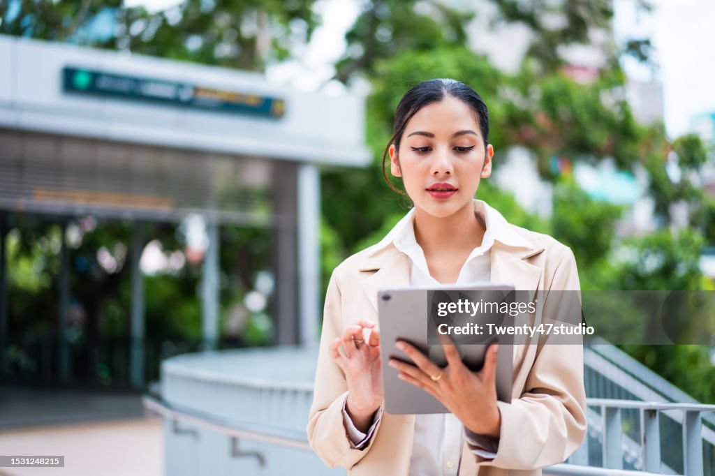 Asian businesswoman using a digital tablet while working outdoors in the city