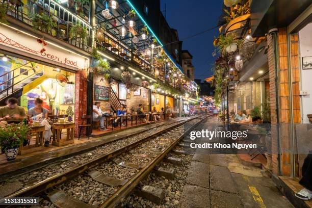 view of train passing through a narrow street of the hanoi old quarter. tourists taking pictures of hurtling train. the hanoi train street is a popular attraction. - hanoi cityscape stock pictures, royalty-free photos & images