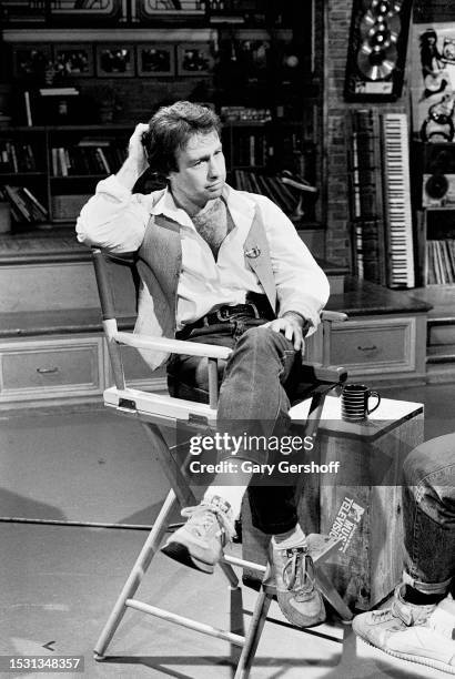 View of British Rock and Blues musician Paul Rodgers seated, cross legged, in a director's chair during an interview on MTV at Teletronic Studios,...