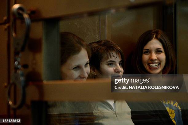 Members of the all-girl punk band "Pussy Riot" Yekaterina Samutsevich, Maria Alyokhina and Nadezhda Tolokonnikova sit in a glass-walled cage in...