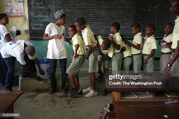 Haitian boys at the L'Ecole Les Freres Clement private elementary school in Jacmel line up to take pills to combat intestinal worms and the virus...