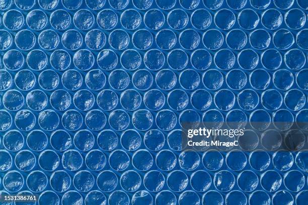 plastic bubble pacik texture against blue background - bubble wrap stock pictures, royalty-free photos & images