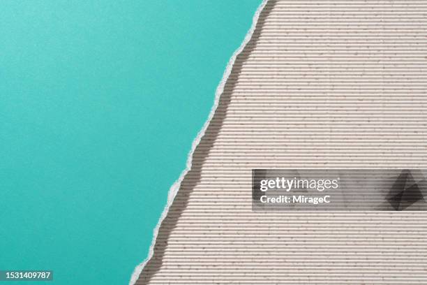 torn turquoise colored paper on beige corrugated paper half by half - querschnitt stock-fotos und bilder