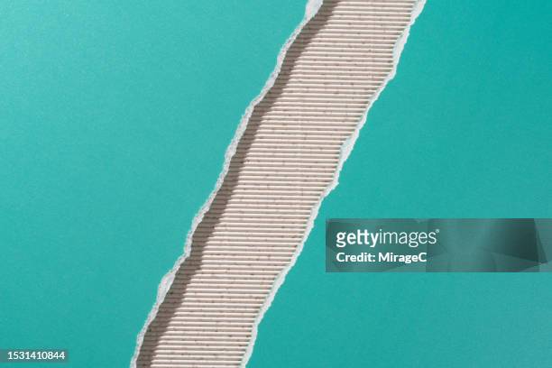 turquoise colored paper torn in half on beige corrugated paper - tearing stockfoto's en -beelden