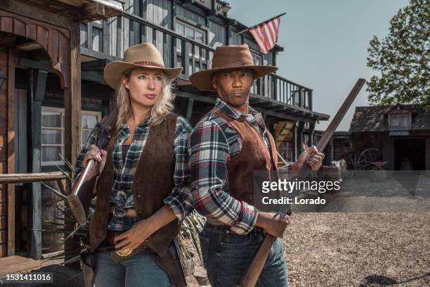 hübscher schwarzer cowboy und schönes blondes cowgirl in einer authentischen wildwest-umgebung - men costume black and white stock-fotos und bilder
