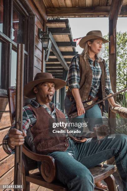 handsome black cowboy and beautiful blonde cowgirl in an authentic wild west setting - sekssymbool stockfoto's en -beelden