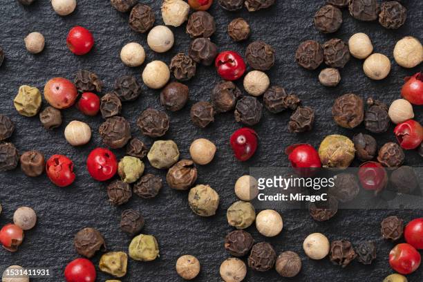 mixed peppercorns on black slate background - scatter stock-fotos und bilder