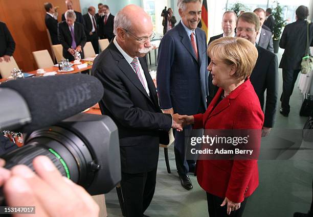 German Chancellor Angela Merkel greets Dieter Zetsche, chairman of Daimler AG , as Peter Loescher, Chief Executive Officer of Siemens AG , looks on...