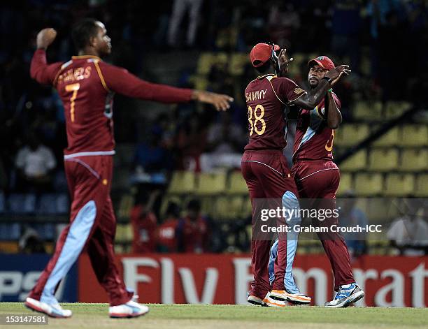 Darren Sammy and Johnson Charles of West Indies celebrate after they ended up tied with New Zealand with a run out from the last ball during the...