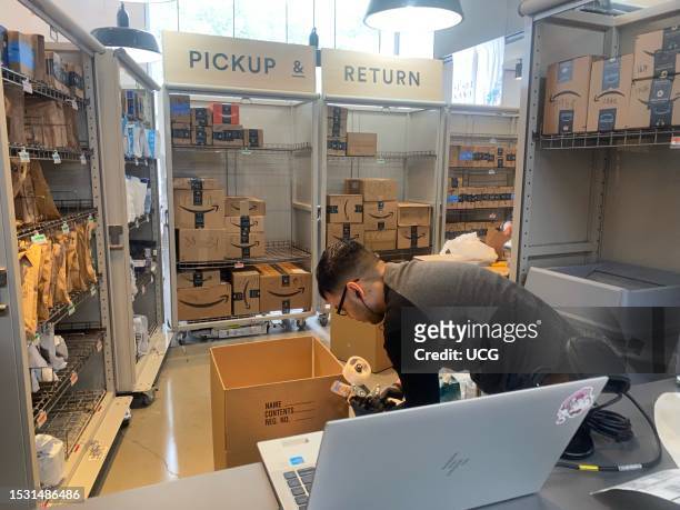 Amazon Pick Up and Return center, an employee packaging up box, Whole Foods, Manhattan, New York.