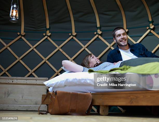 young couple reclining on bed inside yurt. - rundzelt stock-fotos und bilder