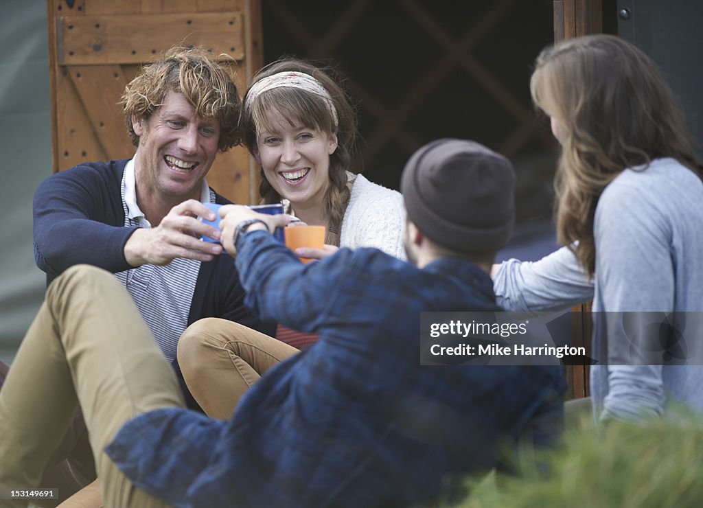 Glamping couples outside yurt sharing a toast.