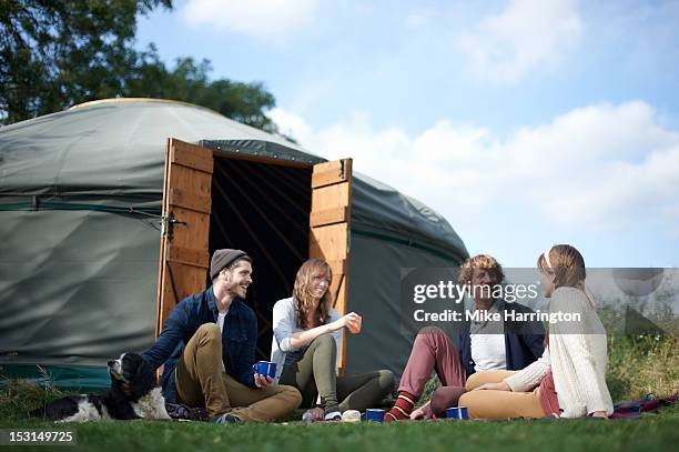 couples sitting outside yurt with drinks. - yurt stock pictures, royalty-free photos & images