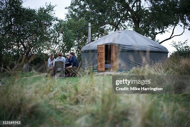 friends conversing at dining table outside yurt. - ger stock pictures, royalty-free photos & images