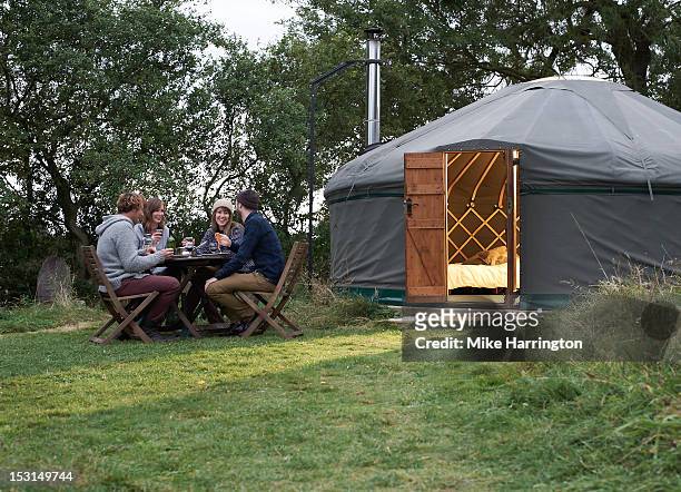 friends enjoying company over dinner outside yurt. - ger stock pictures, royalty-free photos & images