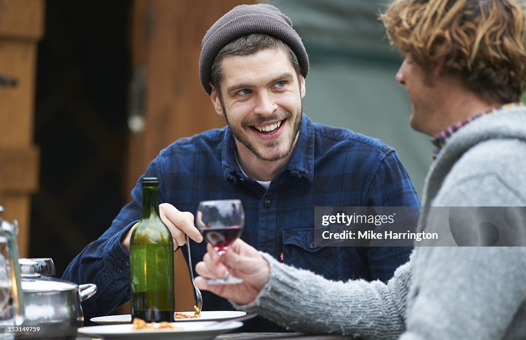 Men conversing over dinner during glamping trip.