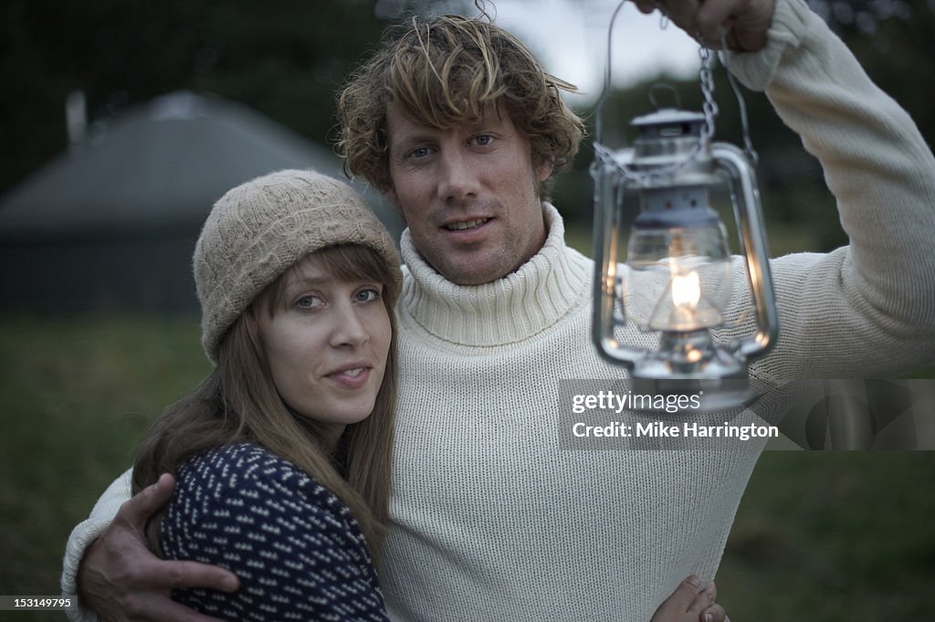 Young couple holding lantern outside yurt.