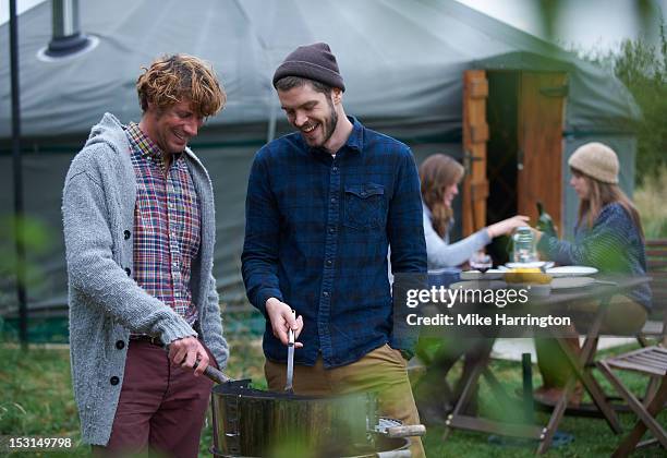 men conversing over barbecue on glamping holiday. - yurt stock pictures, royalty-free photos & images