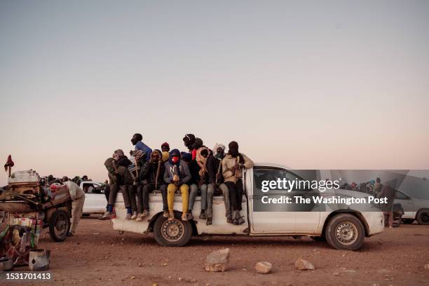 Beaten up trucks sit waiting on the edge of Agadez with crowds of migrants on their way to the Libya border a three day drive away with a convoy....