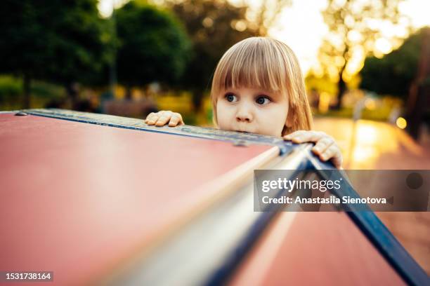 peaking girl at the sunny summer playground - mirar alrededor fotografías e imágenes de stock