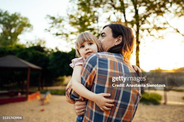 father holding his little daughter at the sunny playground - parent school child stock pictures, royalty-free photos & images